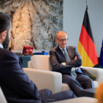 Syria at a Crossroads: Reconstruction, Returns, and Rising Controversy 4 Introduction: A Nation Re-emerging into Global Focus More than a decade after the outbreak of civil war in Syria, the country is once again at the center of international attention. Recent diplomatic developments, economic discussions, and security cooperation efforts suggest a shift in how global powers are engaging with Damascus. At the heart of this renewed focus is the controversial leadership of interim president Ahmed al-Sharaa and a growing willingness from European nations—particularly Germany—to re-engage with Syria politically and economically. This moment reflects a complex intersection of reconstruction ambitions, refugee policies, and geopolitical realities. A Diplomatic Reset: Germany and Syria Rebuild Ties One of the most significant recent developments is Germany’s effort to deepen cooperation with Syria, signaling a notable shift in European foreign policy. German Foreign Minister Johann Wadephul emphasized that Syria holds “enormous” potential as both a market and a production partner. He described the country as a “strategic hub between Europe, the Gulf states and the Indo-Pacific,” highlighting its geographic and economic relevance. This positioning suggests that Syria is no longer viewed solely through the lens of conflict but increasingly as a future economic partner. At a high-level economic forum in Berlin, German officials pledged support for: Rebuilding Syrian state institutions Supporting economic recovery Expanding bilateral trade opportunities Despite ongoing regional instability, Wadephul acknowledged that Syria has managed to prevent broader conflict spillover—calling it “a great success” given tensions across the Middle East. The Al-Sharaa Factor: Leadership, Legitimacy, and Criticism The visit of Ahmed al-Sharaa to Berlin marked a turning point—but also sparked controversy. 4 Al-Sharaa, a 43-year-old former militia leader, has a complex and contentious background. He previously commanded the al-Nusra Front, once linked to extremist networks. His rise to power following the overthrow of Bashar al-Assad in late 2024 has divided international opinion. While some governments see him as a necessary partner for stabilization, critics highlight: Allegations of human rights violations Concerns about minority protection Questions about democratic legitimacy His reception in Berlin reflected this divide. Supporters gathered enthusiastically, chanting “Allahu Akbar,” while protests and political criticism underscored deep unease about legitimizing his leadership. Even within Germany, political and civil society groups remain split. Some argue engagement is essential for peacebuilding, while others warn it risks compromising democratic values. Refugee Returns: Policy, Pressure, and Reality A central issue shaping Germany-Syria relations is the question of refugee repatriation. Germany currently hosts approximately 1 million Syrians, many of whom fled the civil war beginning in 2011. Chancellor Friedrich Merz has proposed an ambitious plan: 80% of Syrians in Germany should return within three years A joint task force will coordinate repatriation efforts Financial support—around €200 million—will assist Syria’s reconstruction However, the policy remains highly controversial. Key Challenges to Repatriation Security concerns: Conditions in Syria are still described as “volatile” Infrastructure damage: Many areas remain heavily destroyed Economic hardship: Limited access to jobs, food, and services Legal risks: Refugees who return may lose protected status abroad Non-governmental organizations have strongly cautioned against forced returns, arguing that safe and dignified conditions are not yet guaranteed. Reconstruction and Economic Opportunity Despite ongoing challenges, Syria is actively positioning itself for reconstruction and investment. Al-Sharaa has framed the country as entering a “new beginning,” emphasizing: Legal reforms to attract foreign investment Opportunities in energy, construction, and technology Efforts to stabilize governance structures Germany and other partners see potential in sectors such as: Infrastructure rebuilding Industrial production IT and software development Energy systems modernization This aligns with broader geopolitical dynamics, where Syria could serve as a logistical and economic bridge between regions. Security Developments: Intelligence and Regional Cooperation Recent events also highlight growing cooperation on security matters. In a notable operation, Turkish intelligence—working with Syrian authorities—captured a fugitive spy at the Syria-Lebanon border after more than a decade on the run. The case underscores: Increasing coordination between regional intelligence agencies Syria’s evolving role in cross-border security Ongoing concerns about espionage and militant networks Such developments suggest that beyond reconstruction, Syria remains a critical player in regional stability and intelligence dynamics. A Fragile Stability in a Volatile Region Despite signs of progress, Syria’s situation remains deeply complex. German officials acknowledge that while conditions have “fundamentally improved,” the broader environment is still unstable. Key risks include: Spillover from regional conflicts (including tensions involving Iran) Internal political fragmentation Ongoing humanitarian challenges Ethnic and sectarian tensions At the same time, Syria has managed—so far—to avoid being drawn into escalating regional conflicts, which some leaders view as a sign of cautious stabilization. What Comes Next: A Critical Turning Point Syria now stands at a pivotal moment. Three parallel trajectories are shaping its future: Reconstruction and economic reintegration Refugee return and demographic shifts Political legitimacy and governance reform The success—or failure—of these efforts will determine whether Syria can transition from a post-conflict state into a stable and functioning nation. Conclusion: Between Opportunity and Uncertainty The re-engagement between Syria and international partners marks a significant shift in global attitudes. Economic cooperation, refugee policy, and security collaboration all point toward a country attempting to rebuild and redefine its role. Yet, the path forward remains uncertain. The leadership of Ahmed al-Sharaa continues to divide opinion, while the realities on the ground challenge optimistic timelines for recovery and repatriation. Syria’s future will depend not only on international support but also on its ability to address internal divisions, rebuild trust, and create conditions for a genuinely inclusive and stable society.